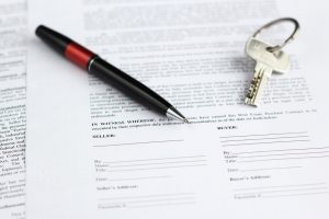 Legal document for sale of real estate with pen and house keys